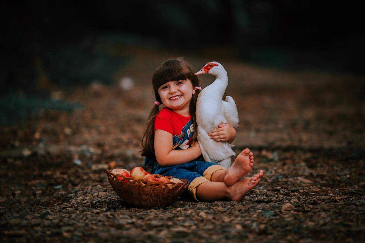 A child interacting with a pet duck, representing the joy and responsibility of first-time pet ownership